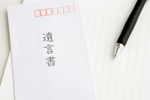 「遺言書」と書かれた白い封筒と、その横に置かれた便箋と黒いボールペン